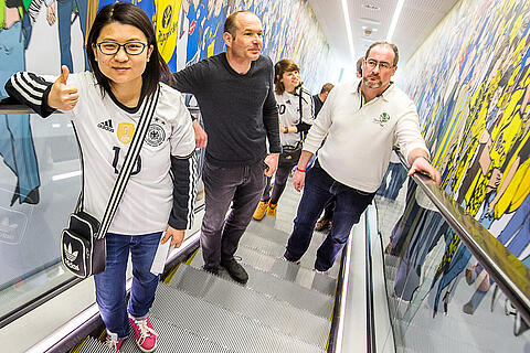 Internationale Gäste fahren mit der Rolltreppe ins 2. Obergeschoss des Deutschen Fußballmuseums, wo die Ausstellung beginnt