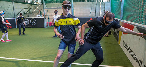 Sehbehinderte spielen Blindenfußball auf dem Spielfeld in der Arena